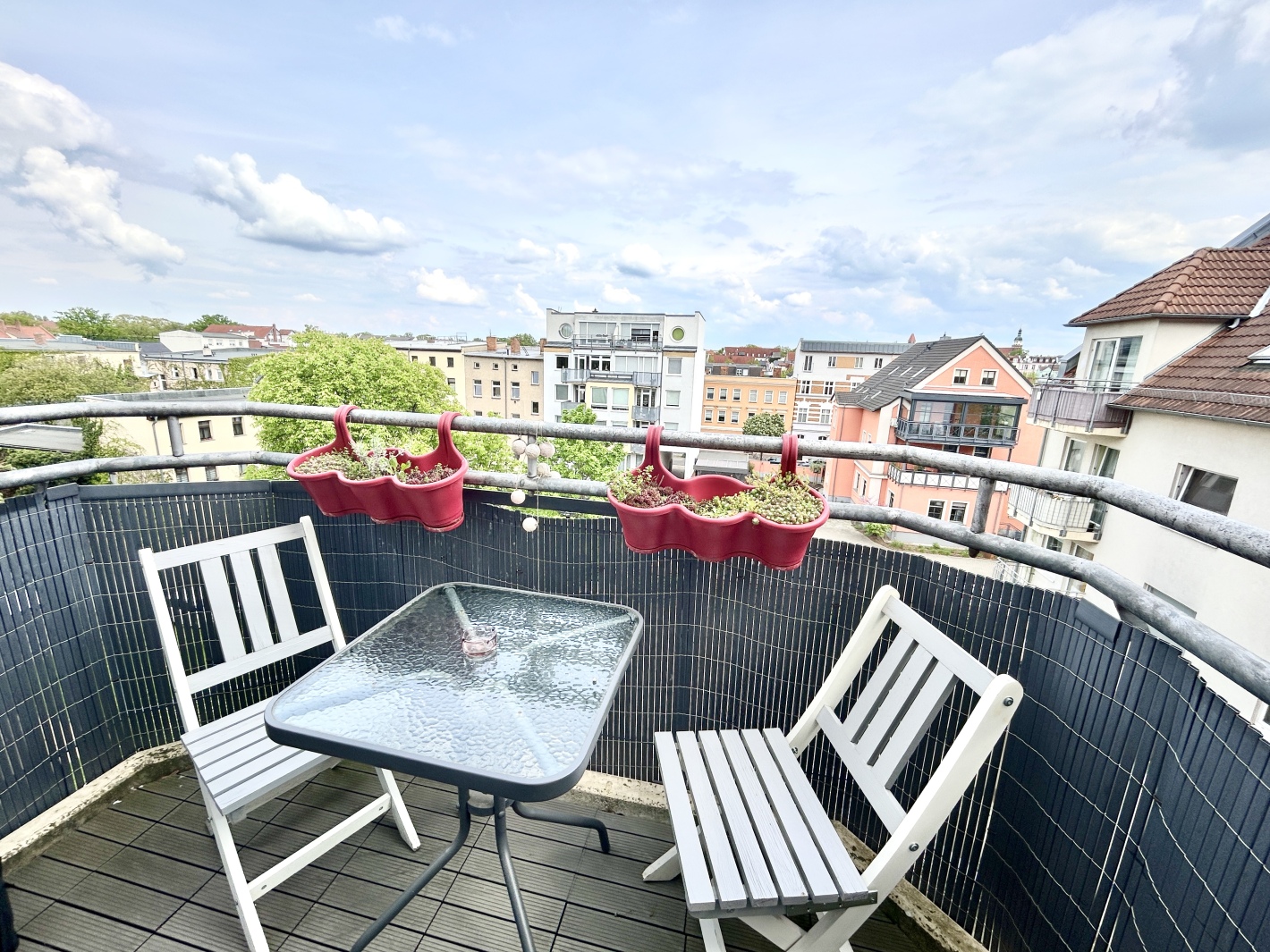 Balkon mit zwei weißen Stühlen und Glastisch im Red Apartment der Ferienwohnung Cottbus