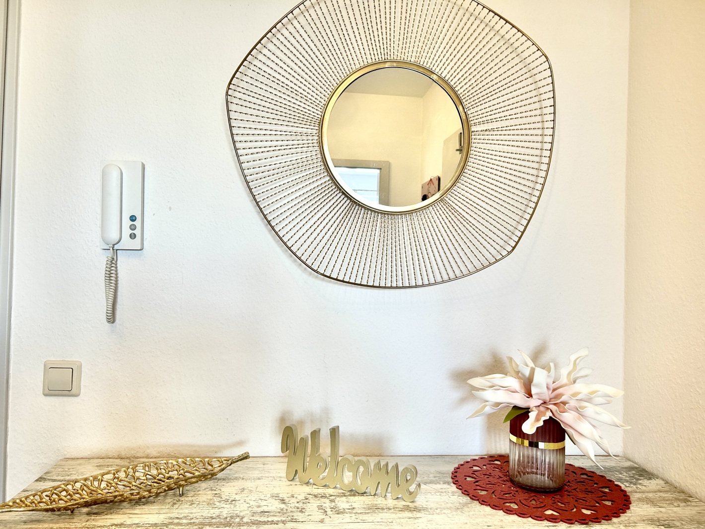 Großer runder Spiegel mit Deko im Flur der Ferienwohnung Cottbus Red Apartment
