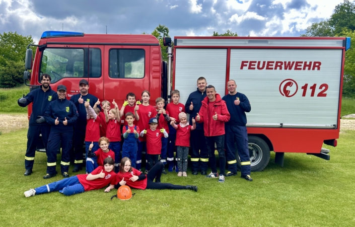 Kidner der Jugendfeuerwehr Cottbus vor einem Feuerwehrauto erhalten eine Spende von Cottbus-Apartments