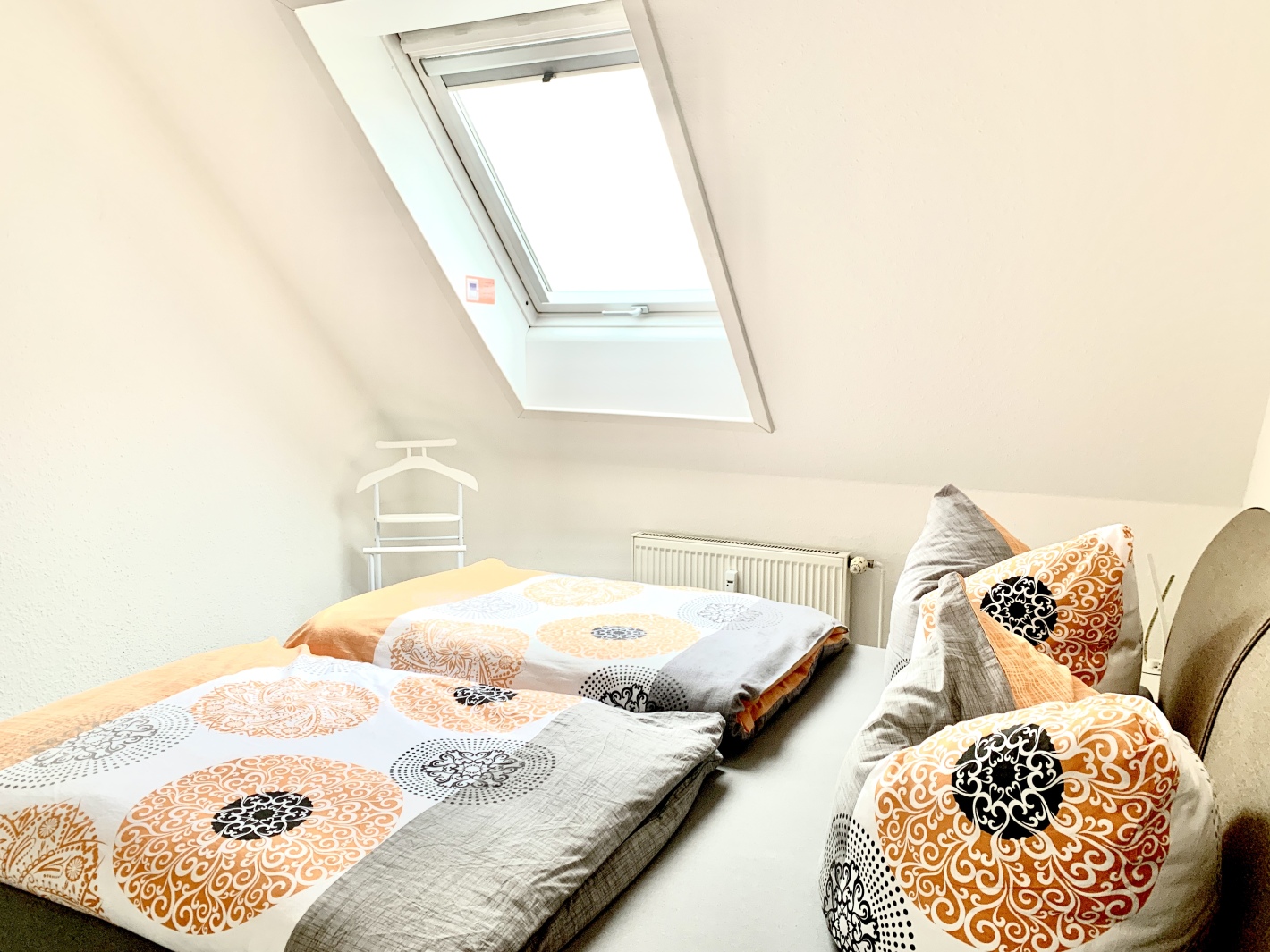 Gemütliches Bett unter Dachfenster im Schlafzimmer der Ferienwohnung Cottbus mit Balkon