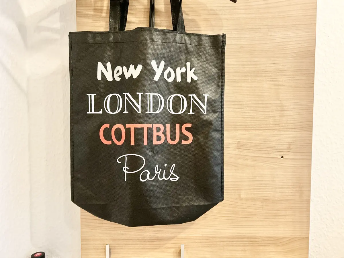 ferienwohnung-cottbus-green-apartment-assesoire Schwarzer Stoffbeutel mit der Aufschrift „New York, London, COTTBUS, Paris“ als lokales Accessoire im Green Apartment Cottbus.