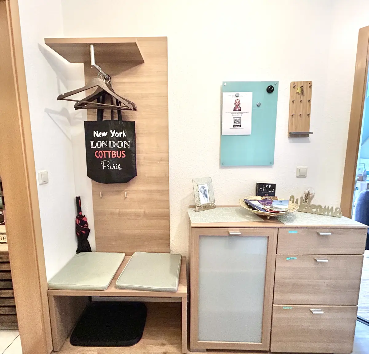 ferienwohnung-cottbus-green-apartment-flur-kommode Moderne Garderobe und Holzkommode im Flur des Green Apartments Cottbus – praktischer Stauraum in Ihrer zentralen Unterkunft.