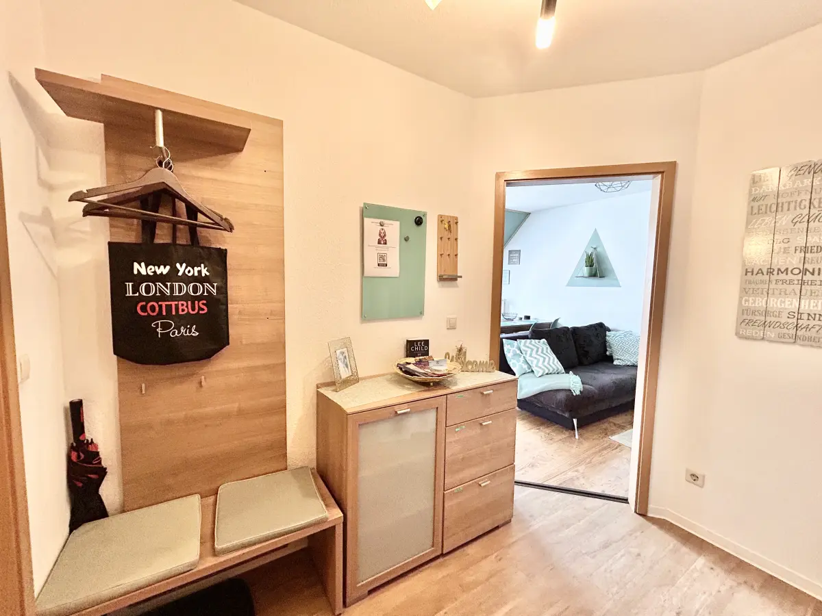 ferienwohnung-cottbus-green-apartment-flur-zum-wohnzimmer Helle Garderobe und Flur im Green Apartment Cottbus mit offenem Blick in das gemütliche Wohnzimmer.