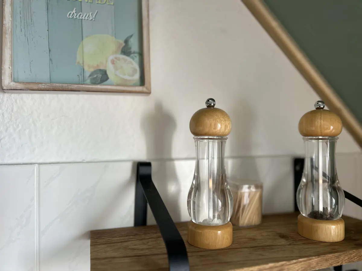 ferienwohnung-cottbus-green-apartment-kuechenzeile-Salzstreuer Salz- und Pfefferstreuer auf einem Holzregal in der voll ausgestatteten Küche des Green Apartments – Ihre zentrale Ferienwohnung in Cottbus.